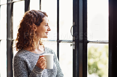 Buy stock photo Shot of a mature woman standing in her home drinking a coffee and looking through a window