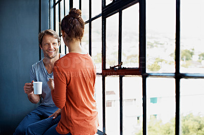 Buy stock photo Shot of a happy mature couple sitting on a window sill at home drinking coffee and talking together