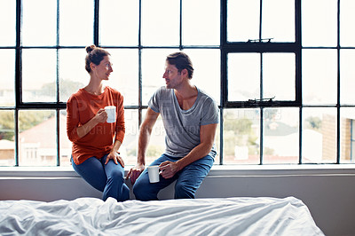 Buy stock photo Shot of a happy mature couple sitting on a window sill at home drinking coffee and talking together