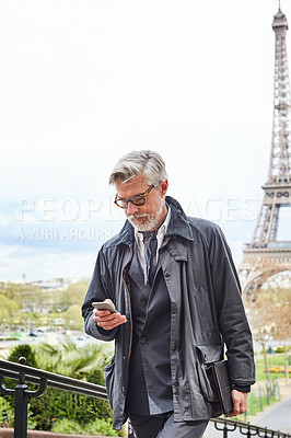 Buy stock photo Shot of a handsome mature man using a cellphone in Paris with the Eiffel Tower in the background