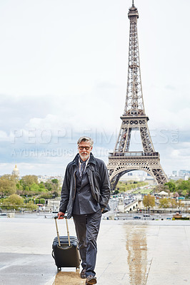 Buy stock photo Portrait of a handsome mature man walking with his suitcase in front of the Eiffel Tower