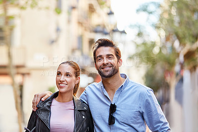 Buy stock photo Shot of an affectionate young couple walking together in the city
