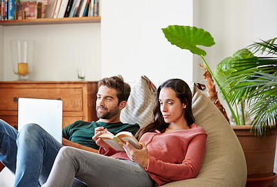 Buy stock photo Shot of a smiling young couple relaxing together on a beanbag sofa at home