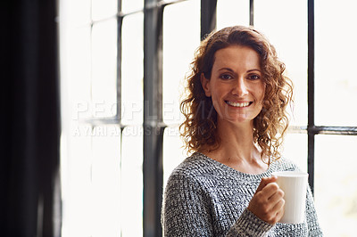 Buy stock photo Portrait of a mature woman standing in her home drinking a coffee and looking through a window
