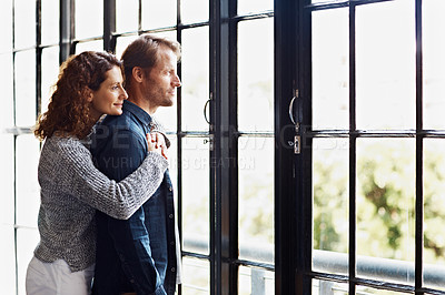 Buy stock photo Shot of an affectionate mature couple hugging in front of a window at home