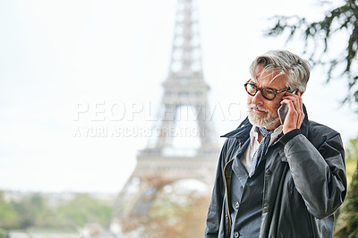 Buy stock photo Shot of a handsome mature man talking on a cellphone in Paris with the Eiffel Tower in the background