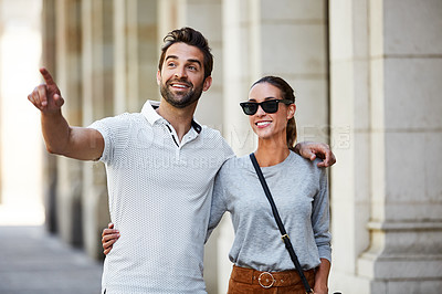 Buy stock photo Shot of an affectionate young couple walking together in the city