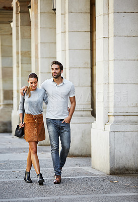 Buy stock photo Shot of an affectionate young couple walking together in the city