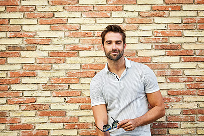 Buy stock photo Portrait of a stylish young man leaning against a brick wall outside