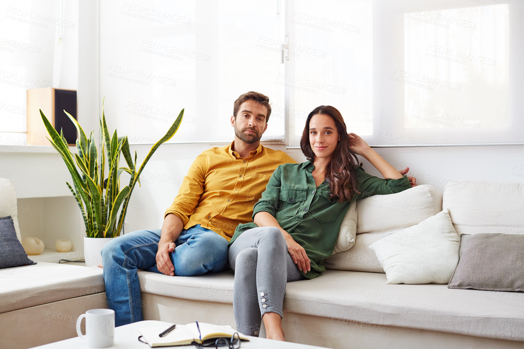 Buy stock photo Portrait of a young couple relaxing together on their living room sofa