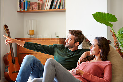 Buy stock photo Shot of a smiling young couple talking together while relaxing in their living room