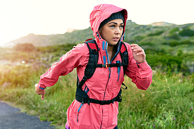 Buy stock photo Shot of a focused young woman out for a run on a cool morning
