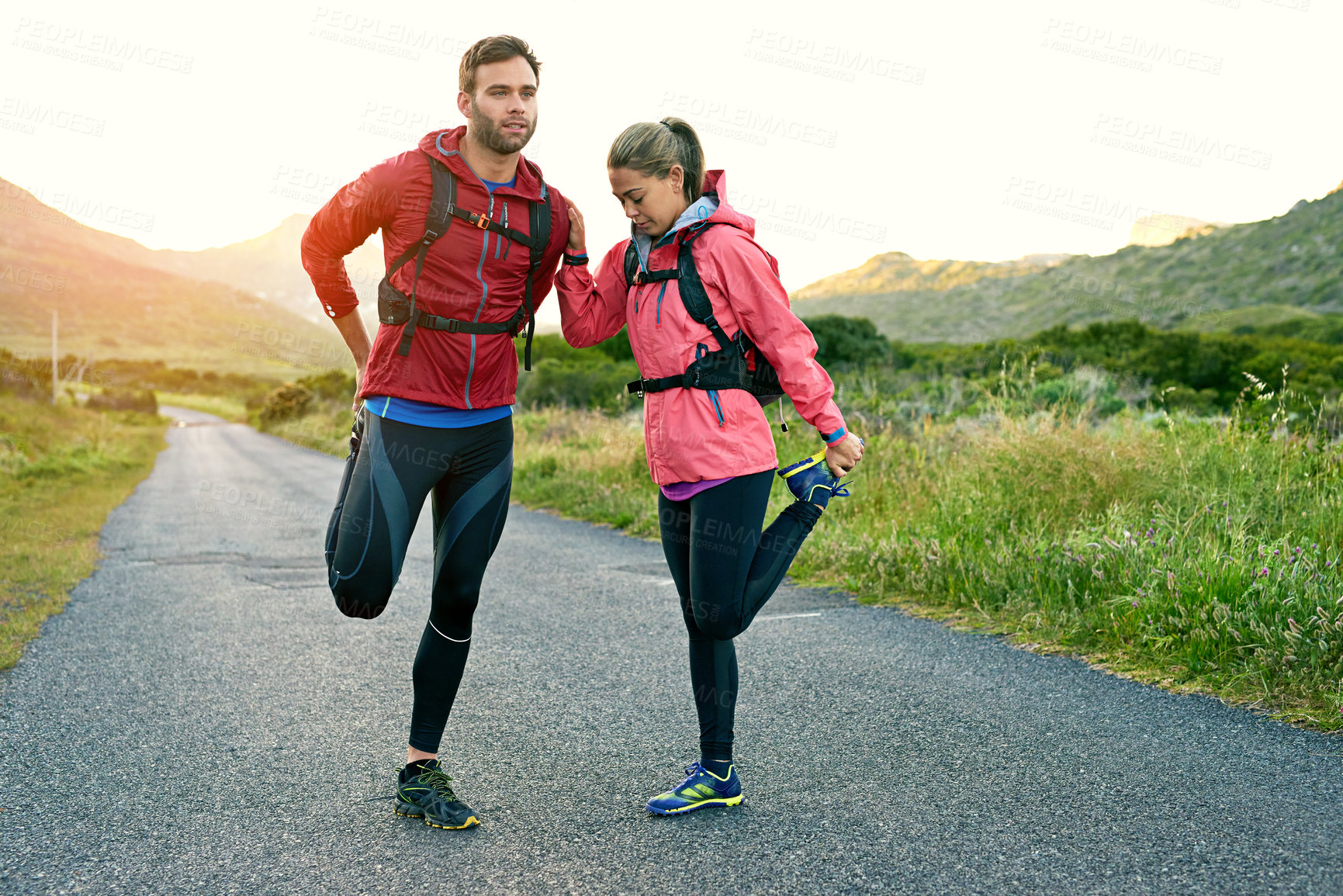 Buy stock photo Shot of two friends stretching before a run on a cool morning