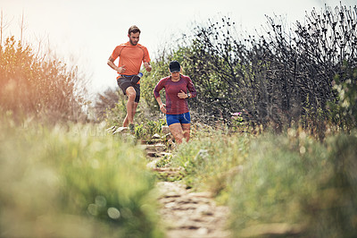 Buy stock photo Shot of two young friends running together along a trail