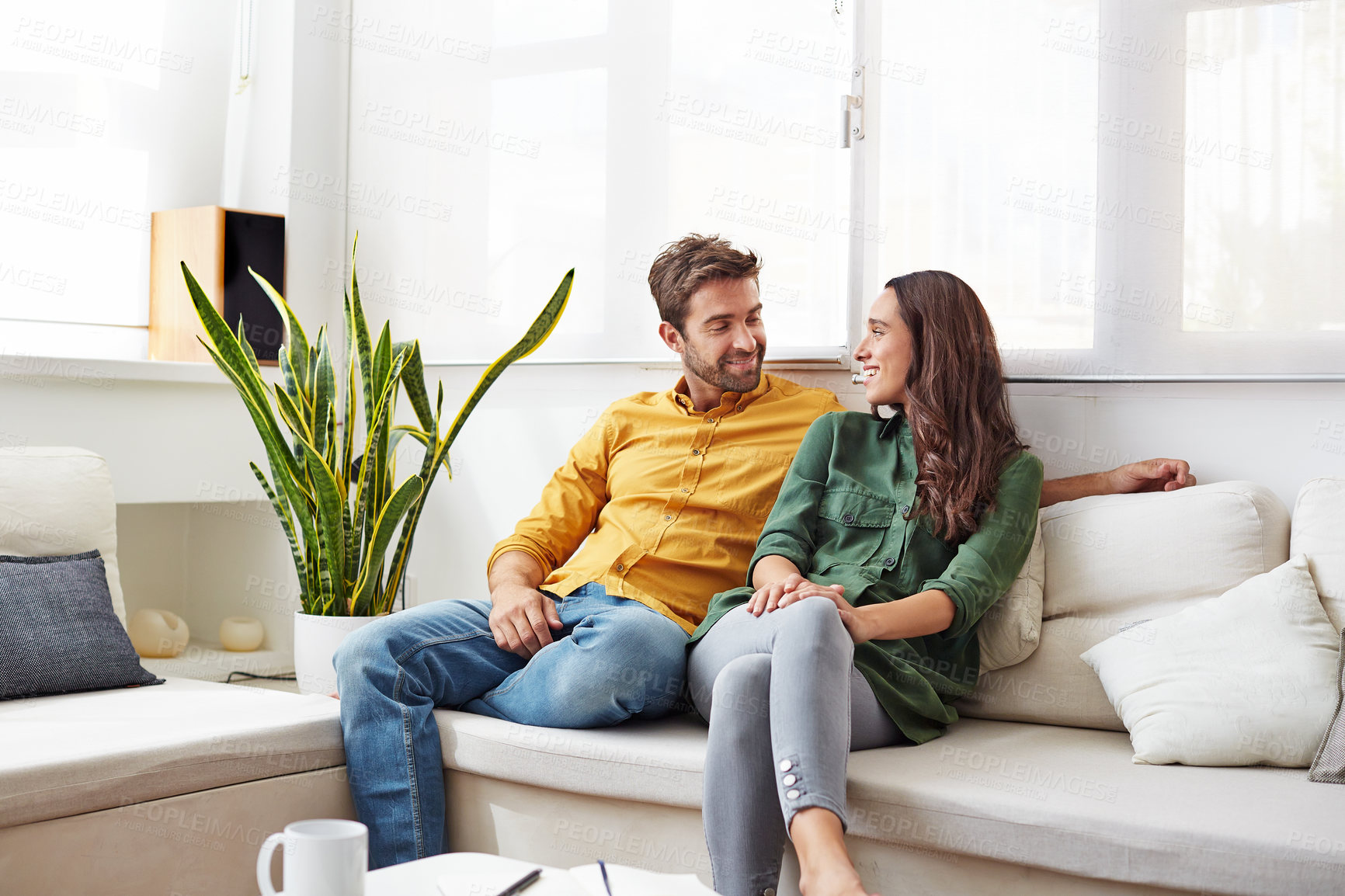Buy stock photo Shot of a smiling young couple talking together while relaxing in their living room