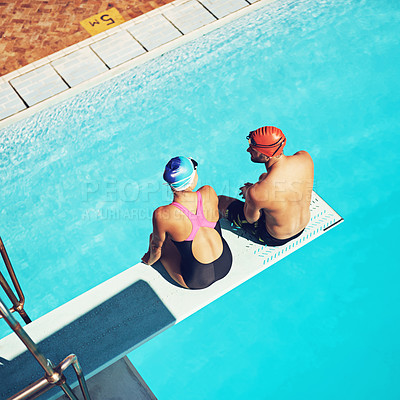 Buy stock photo High angle shot of two swimmers sitting on a diving board above a swimming pool