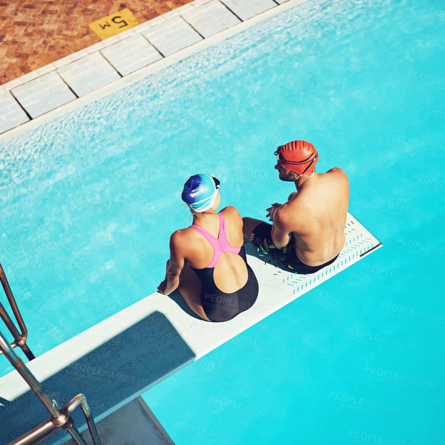 Buy stock photo High angle shot of two swimmers sitting on a diving board above a swimming pool