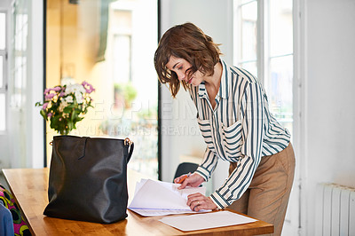 Buy stock photo Shot of an attractive young businesswoman looking over some paperwork in the office