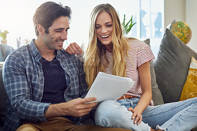 Buy stock photo Shot of an affectionate young couple looking over some paperwork at home