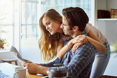 Buy stock photo Shot of an affectionate young couple looking over some paperwork at home