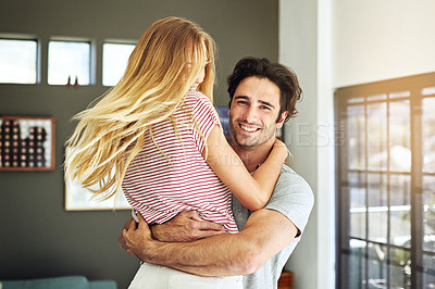 Buy stock photo Shot of a handsome young man embracing his girlfriend in their home