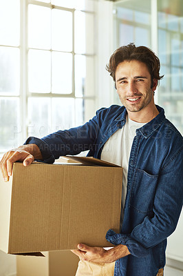 Buy stock photo Shot of a handsome young man carrying a box while moving house