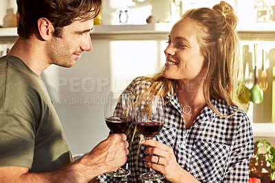 Buy stock photo Shot of an affectionate young couple making a toast while drinking red wine