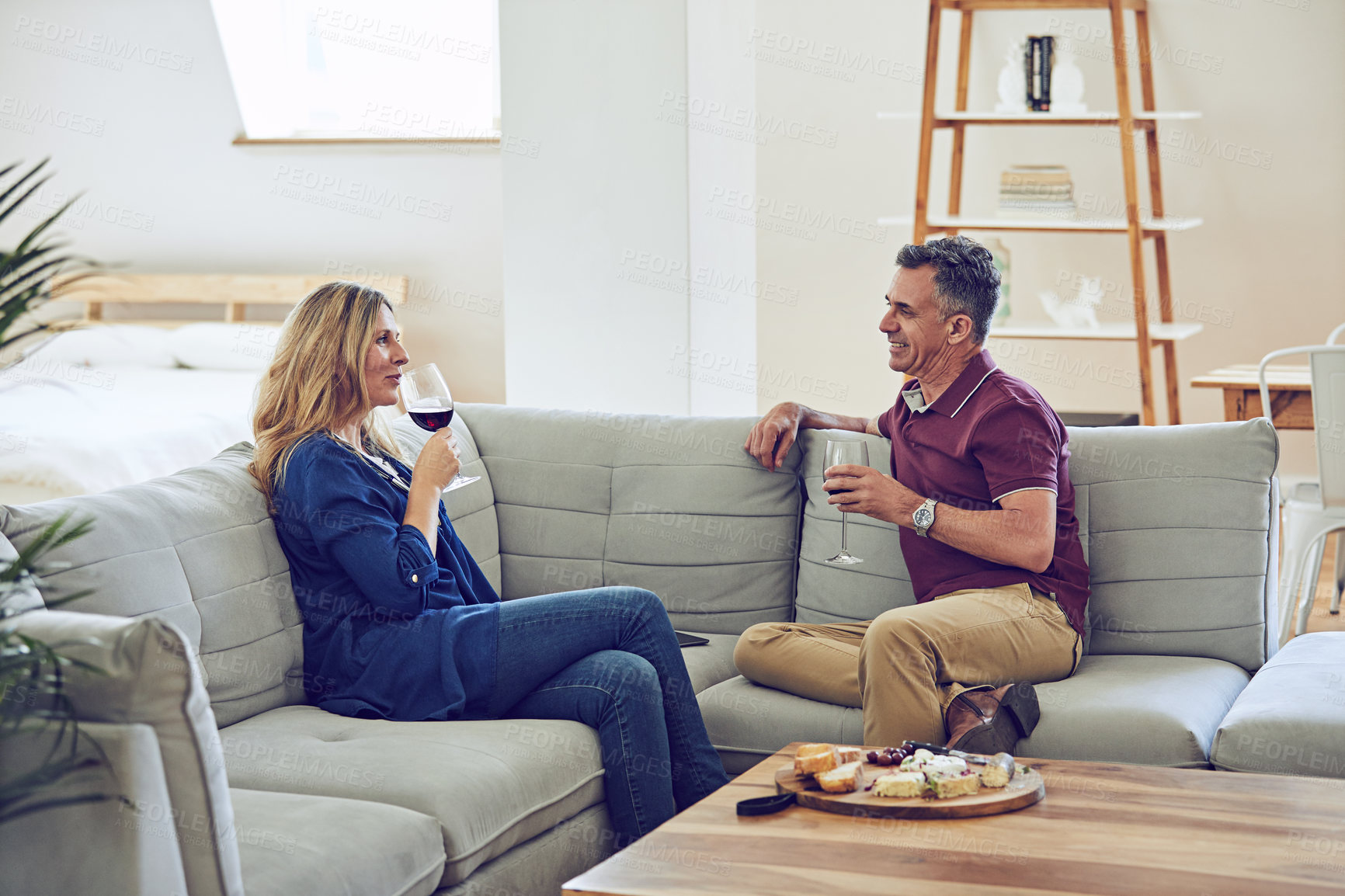 Buy stock photo Shot of an affectionate mature couple having cheese and wine on the sofa at home