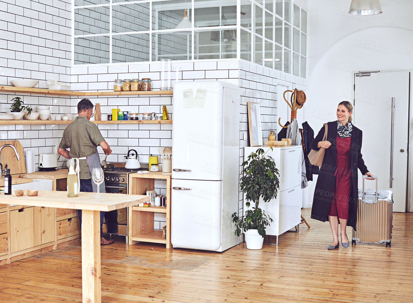 Buy stock photo Shot of a mature woman arriving home to her husband cooking in the kitchen