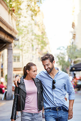 Buy stock photo Shot of an affectionate young couple walking together in the city