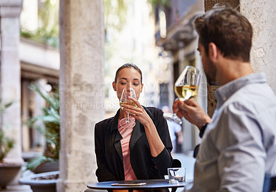Buy stock photo Shot of a young couple sitting at a sidewalk table drinking wine and talking together