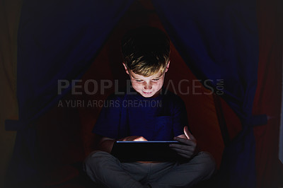 Buy stock photo Shot of a little boy using a tablet while sitting down on his bed