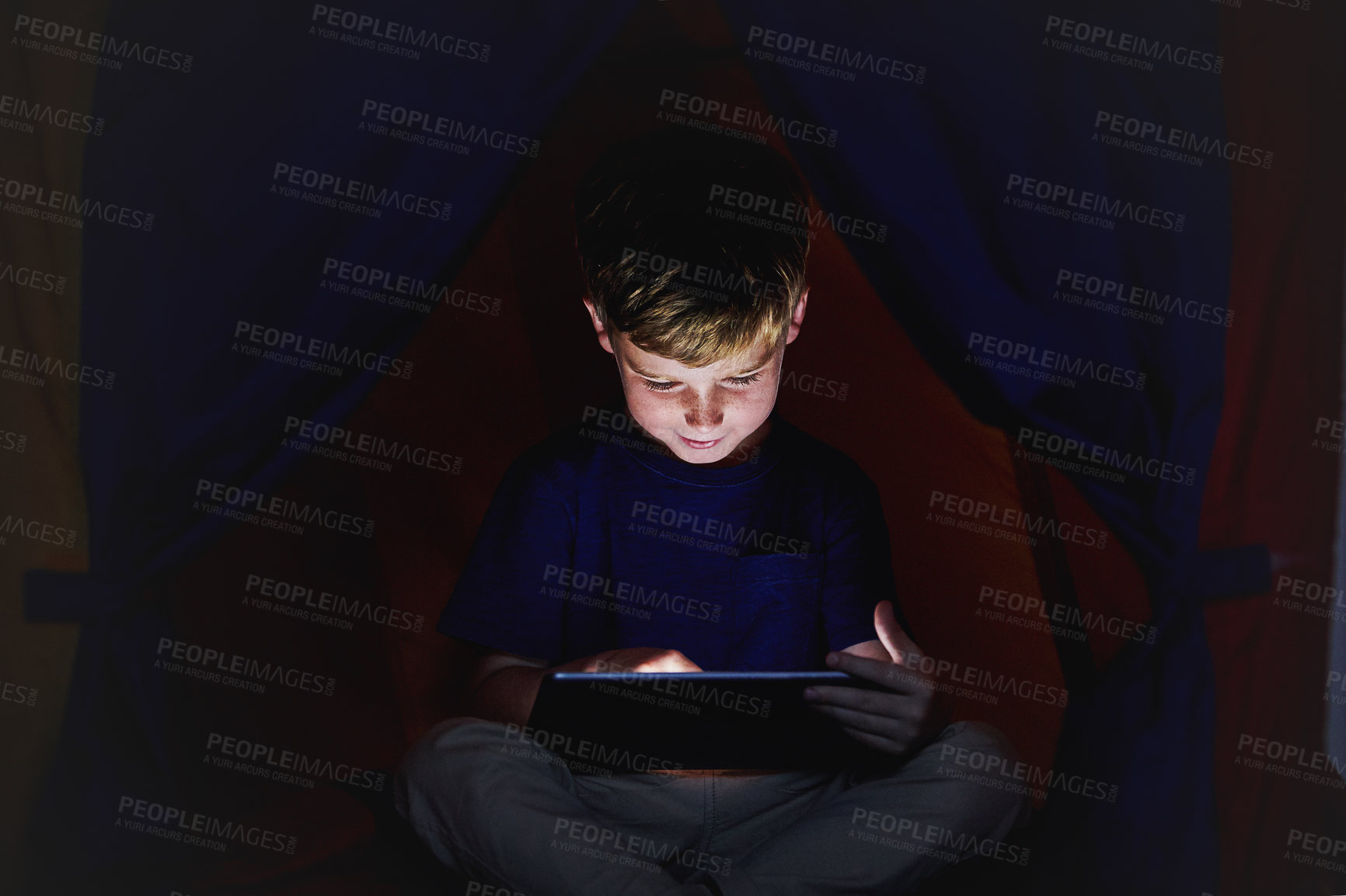 Buy stock photo Shot of a little boy using a tablet while sitting down on his bed