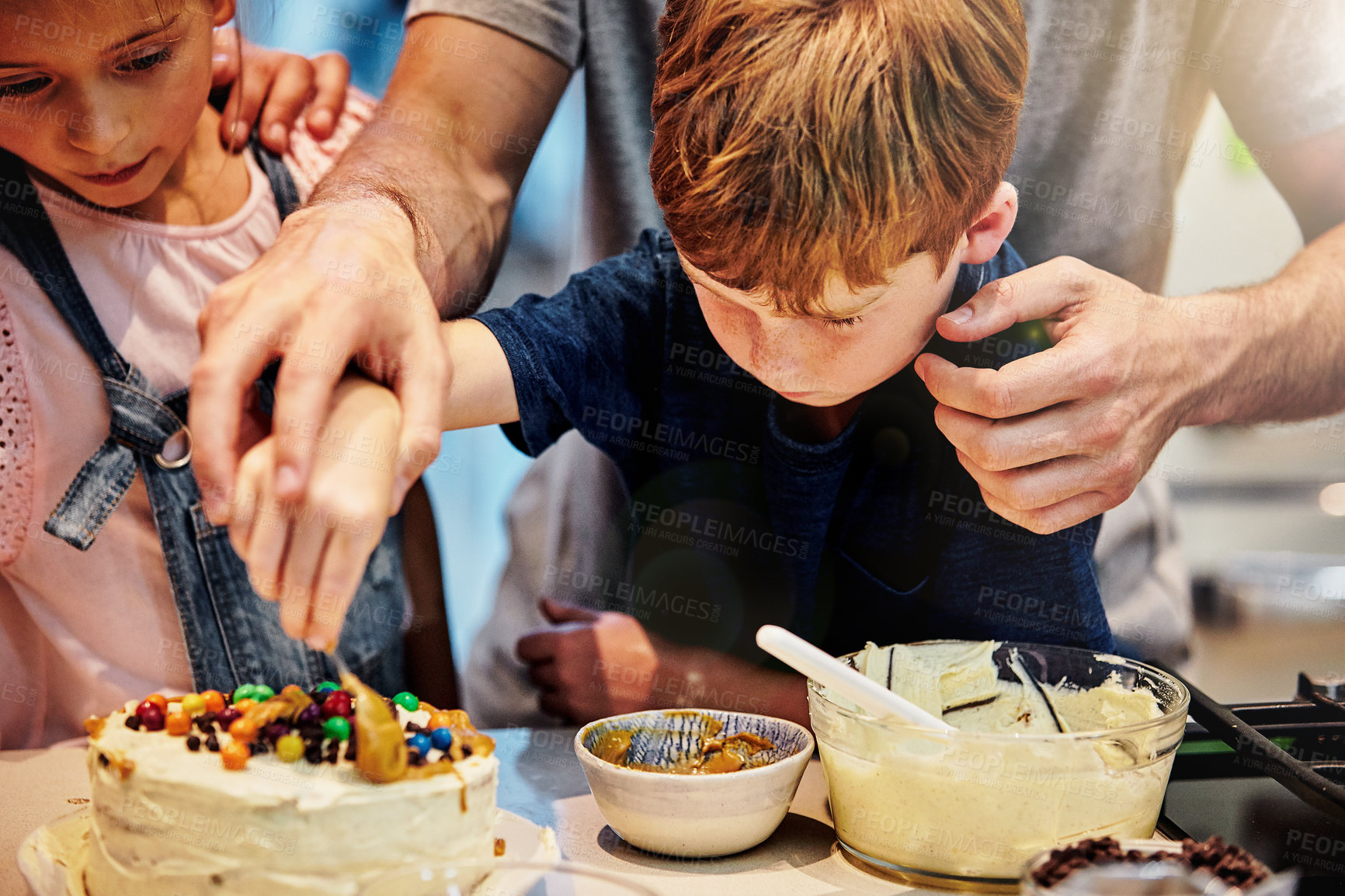 Buy stock photo Shot of a young father baking a cake with his son and daughter