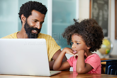 Buy stock photo Shot of a cheerful young father and son browsing on a digital tablet together while being seated at a table in their home