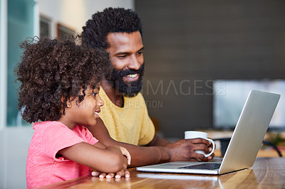 Buy stock photo Shot of a cheerful young father and son browsing on a digital tablet together while being seated at a table in their home