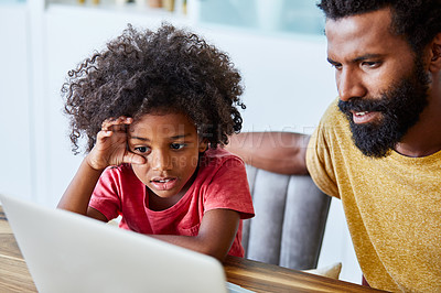 Buy stock photo Shot of a cheerful young father and son browsing on a digital tablet together while being seated at a table in their home