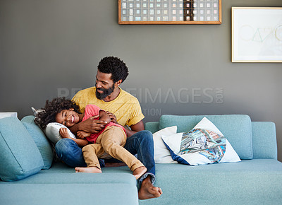Buy stock photo Shot of a cheerful young father and son relaxing on a couch at home during the day
