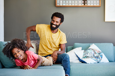 Buy stock photo Portrait of a cheerful young man playing with his son while being seated on the couch