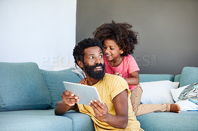 Buy stock photo Shot of a cheerful young father and his son browsing on a digital tablet while being seated on a couch at home