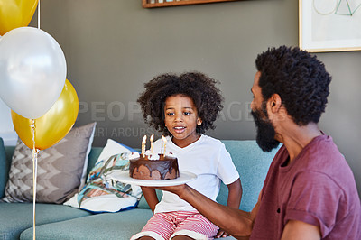 Buy stock photo Shot of a cheerful little boy receiving a birthday cake from his dad inside at home during the day