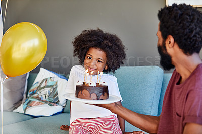 Buy stock photo Shot of a cheerful little boy receiving a birthday cake from his dad inside at home during the day