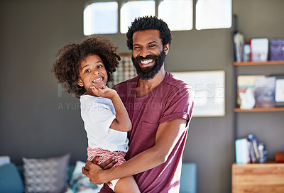 Buy stock photo Portrait of a cheerful young father holding his son while looking at the camera inside at home during the day