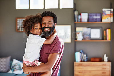 Buy stock photo Portrait of a cheerful young father holding his son while looking at the camera inside at home during the day