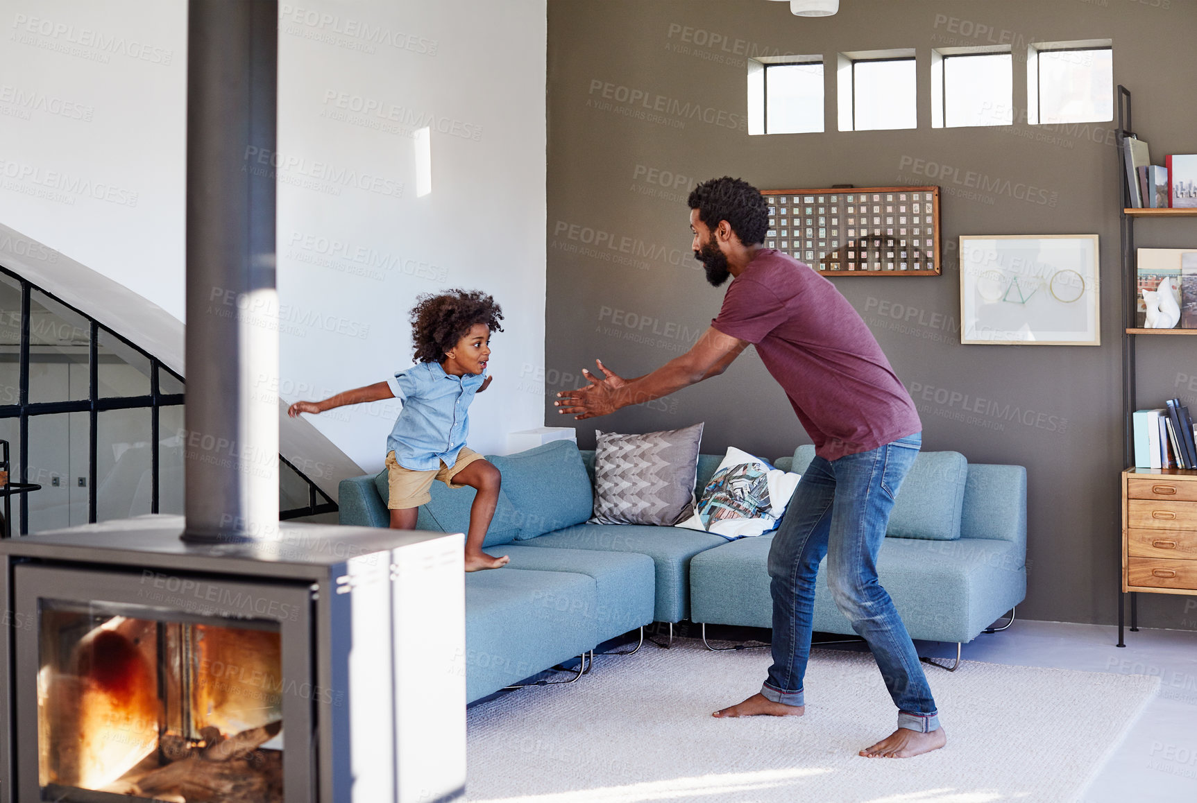Buy stock photo Shot of a cheerful young father and son playing around in the living room inside at home during the day