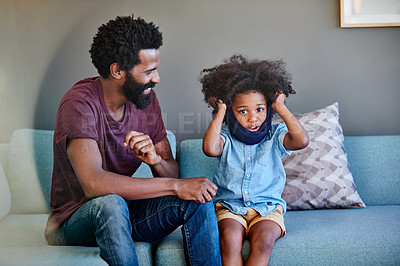 Buy stock photo Shot of a cheerful father and son seated on a couch while playing around in the living room at home