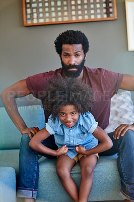 Buy stock photo Portrait of a cheerful father and son flexing their muscles while being seated on a couch at home during the day