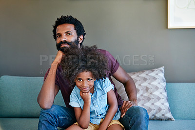 Buy stock photo Portrait of a cheerful father and son striking a pose while being seated on the couch at home during the day