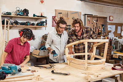 Buy stock photo Shot of three people working with wood in a furniture manufacturing workshop