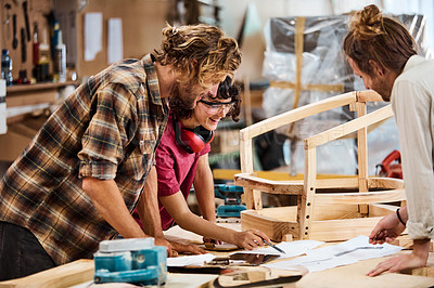 Buy stock photo Shot of three people working with wood in a furniture manufacturing workshop
